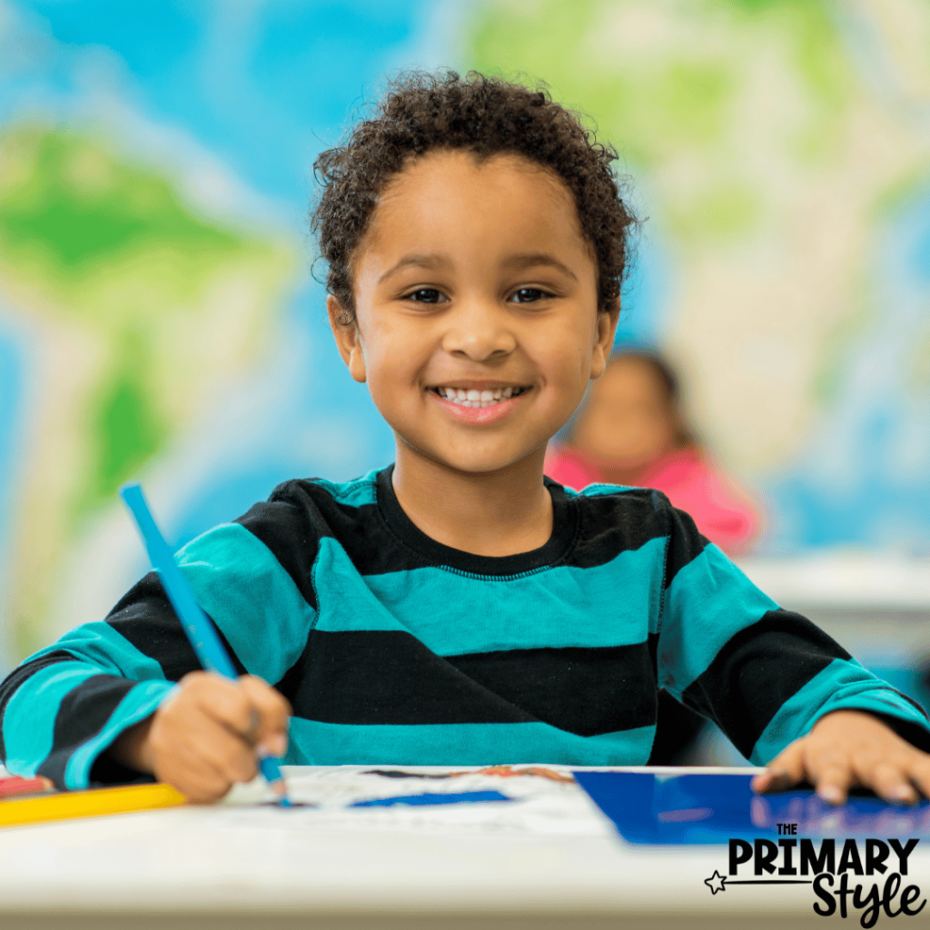 This image shows a student coloring at their desk and smiling.